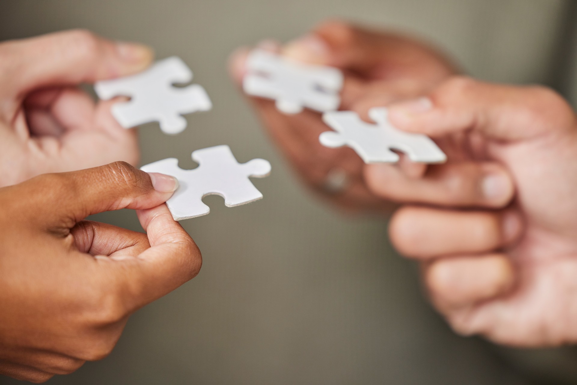 Business people, hands and puzzle piece for collaboration, planning or team building strategy at office. Hand of group in teamwork for goal, support or motivation in cooperation for problem solving